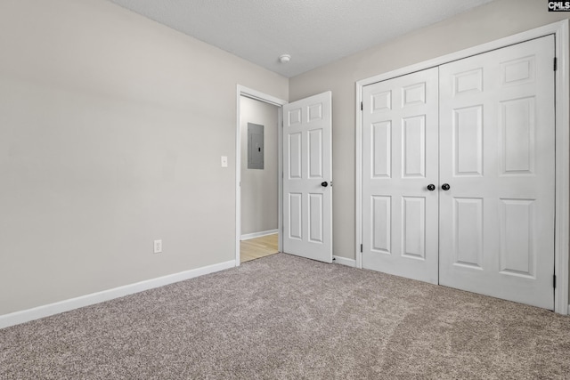 unfurnished bedroom with electric panel, baseboards, a textured ceiling, carpet flooring, and a closet