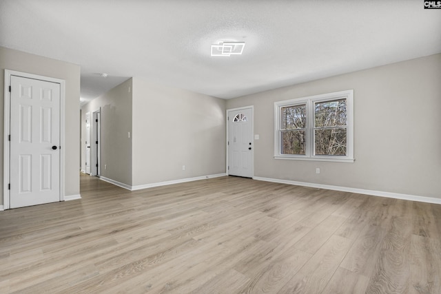 interior space with baseboards, visible vents, a textured ceiling, and light wood finished floors