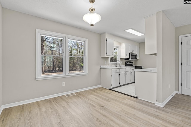 kitchen featuring stainless steel appliances, light wood-type flooring, light countertops, and baseboards