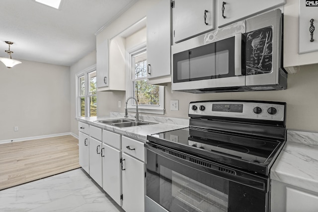 kitchen featuring marble finish floor, light countertops, stainless steel microwave, electric range, and a sink