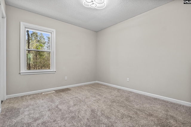 carpeted empty room featuring visible vents, baseboards, and a textured ceiling