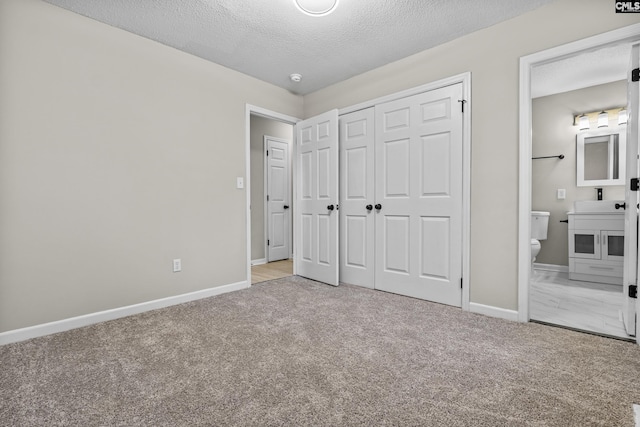 unfurnished bedroom featuring a closet, carpet flooring, a textured ceiling, and baseboards