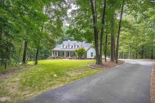 new england style home with driveway, a porch, and a front yard