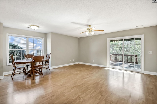 dining space with a textured ceiling, wood finished floors, a wealth of natural light, and baseboards