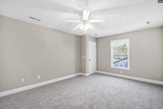 unfurnished room with a textured ceiling, light carpet, visible vents, baseboards, and a ceiling fan