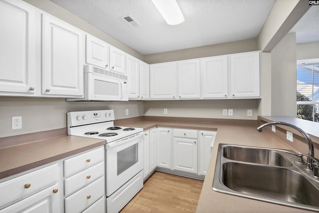 kitchen featuring white appliances, a sink, visible vents, white cabinets, and light wood-style floors