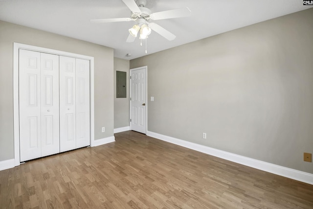 unfurnished bedroom featuring electric panel, baseboards, and wood finished floors