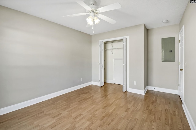 unfurnished bedroom featuring light wood-type flooring, electric panel, baseboards, and a closet