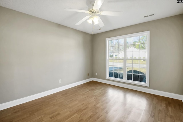 unfurnished room featuring a ceiling fan, visible vents, baseboards, and wood finished floors