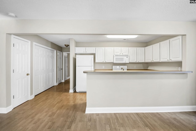 kitchen with light wood finished floors, light countertops, white cabinetry, white appliances, and baseboards