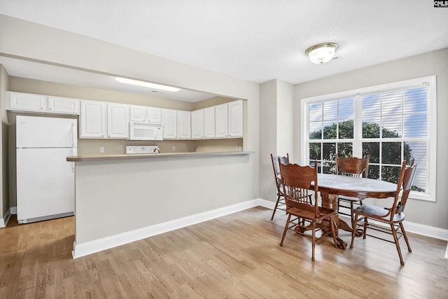 dining area featuring light wood-style floors and baseboards