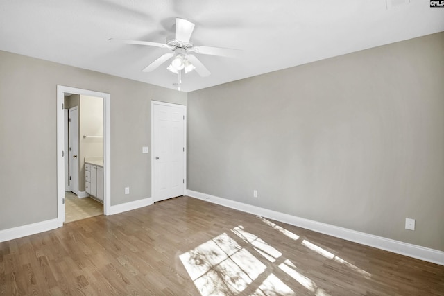 unfurnished bedroom with baseboards, connected bathroom, and light wood-style floors