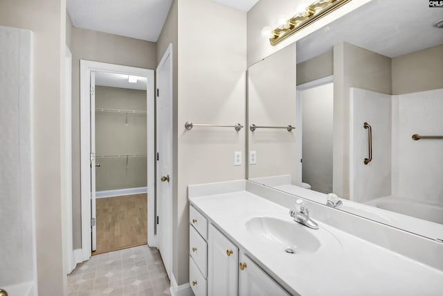 bathroom featuring a shower, vanity, toilet, and a spacious closet