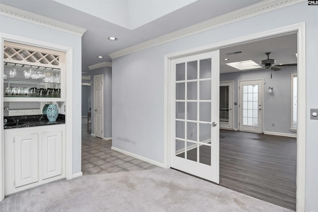 interior space with ceiling fan, recessed lighting, baseboards, a bar, and crown molding