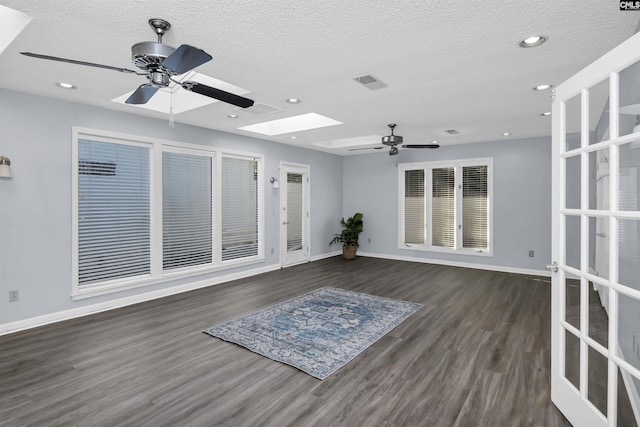 spare room featuring a skylight, wood finished floors, and baseboards