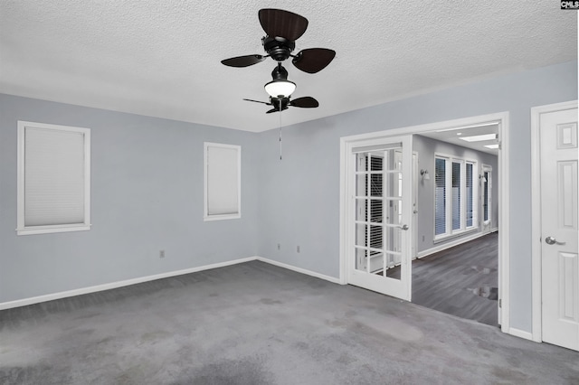 empty room with a ceiling fan, carpet, a textured ceiling, and baseboards