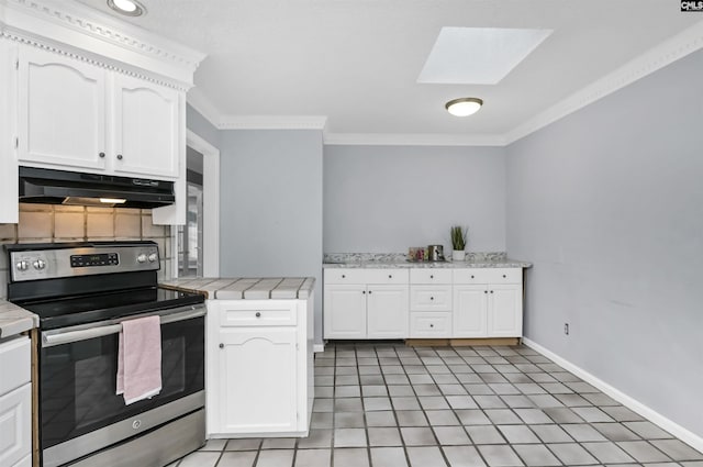 kitchen with tile countertops, ornamental molding, stainless steel electric stove, under cabinet range hood, and white cabinetry