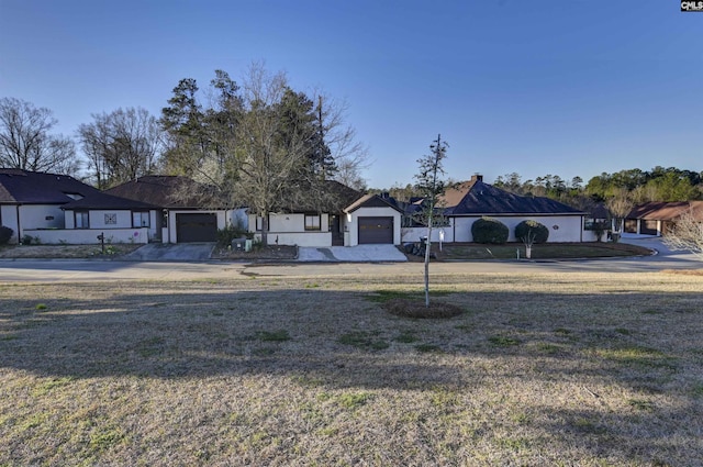 view of front of house with concrete driveway, an attached garage, and a front lawn