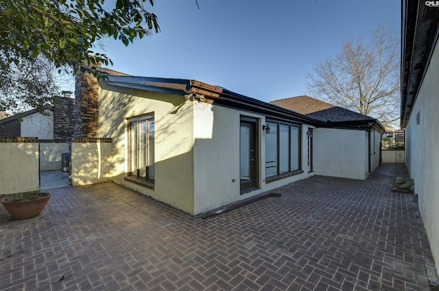 view of property exterior featuring stucco siding, fence, and a patio