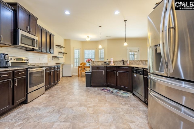 kitchen with decorative light fixtures, stainless steel appliances, tasteful backsplash, dark brown cabinets, and a peninsula