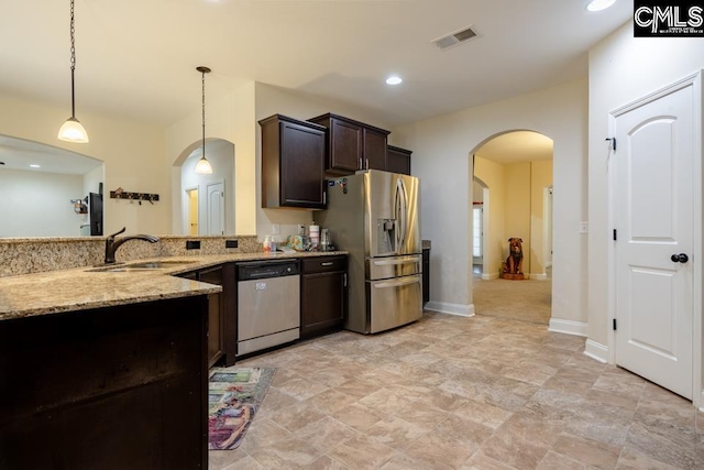 kitchen featuring arched walkways, light stone counters, a sink, visible vents, and appliances with stainless steel finishes