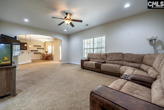 living room with recessed lighting, arched walkways, and light colored carpet