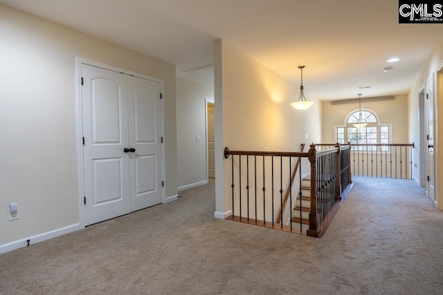 hallway featuring baseboards, carpet flooring, and an upstairs landing