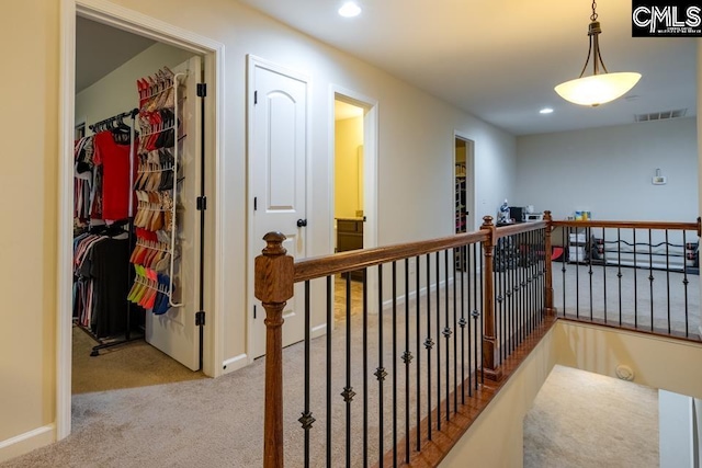 hallway with carpet, an upstairs landing, visible vents, and recessed lighting