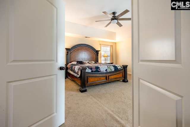 bedroom with carpet floors, visible vents, a raised ceiling, and a ceiling fan