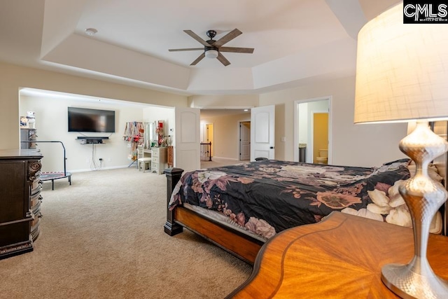 carpeted bedroom featuring baseboards, a raised ceiling, and a ceiling fan