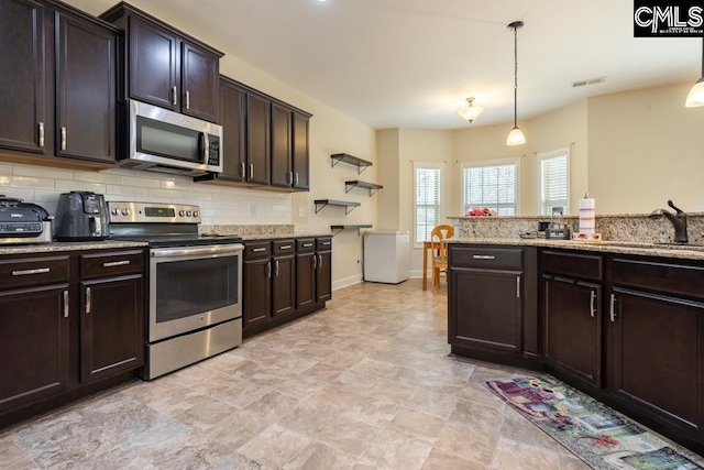 kitchen with stainless steel appliances, a sink, visible vents, decorative backsplash, and pendant lighting