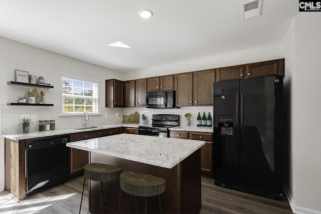 kitchen with black appliances, dark wood finished floors, a sink, and visible vents