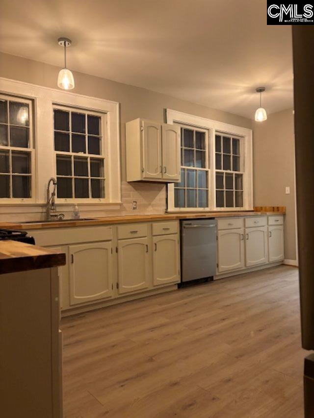 kitchen featuring decorative light fixtures, a sink, light wood-style flooring, and stainless steel dishwasher