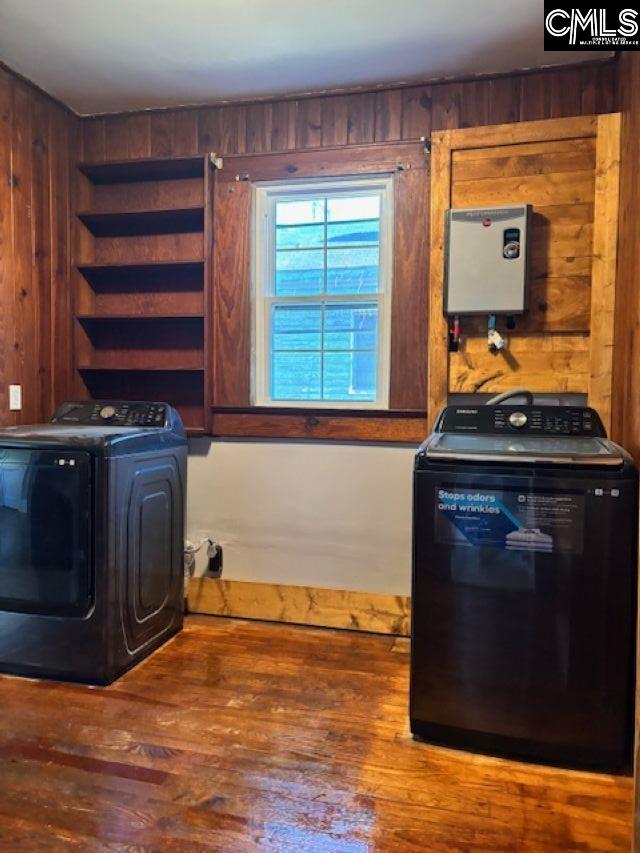 laundry room with independent washer and dryer, laundry area, wood walls, and wood finished floors