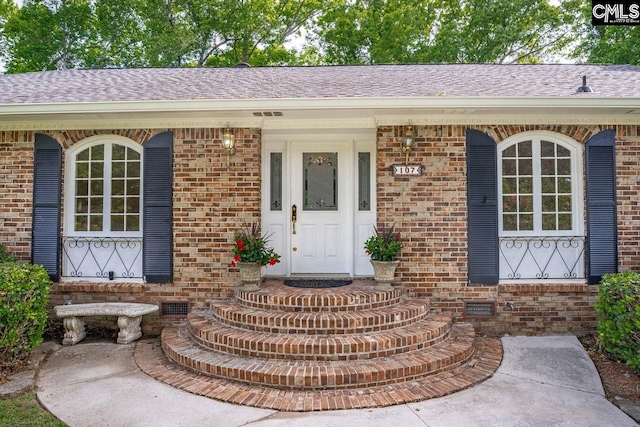 doorway to property with crawl space, roof with shingles, and brick siding