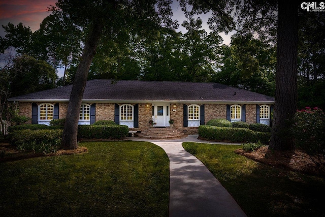 ranch-style home featuring a front lawn and brick siding