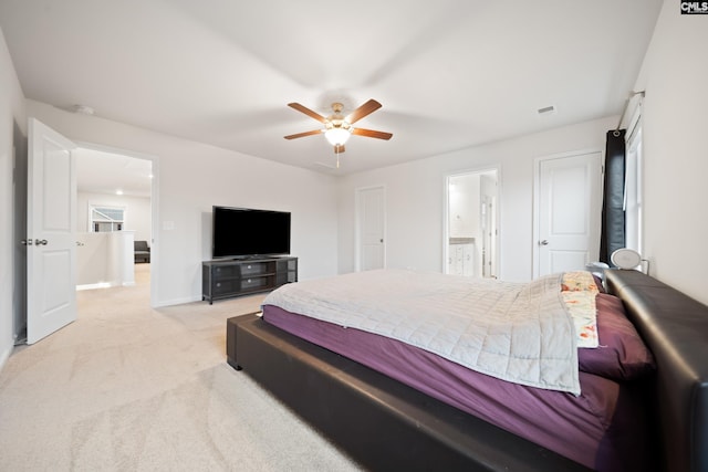 bedroom with visible vents, light colored carpet, a ceiling fan, ensuite bath, and baseboards