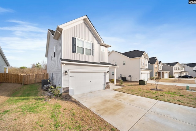 view of front facade featuring an attached garage, fence, concrete driveway, a residential view, and board and batten siding