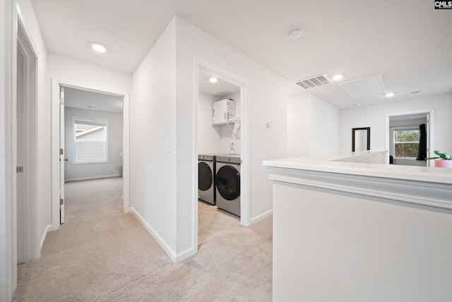 hall featuring visible vents, attic access, washing machine and dryer, light carpet, and baseboards