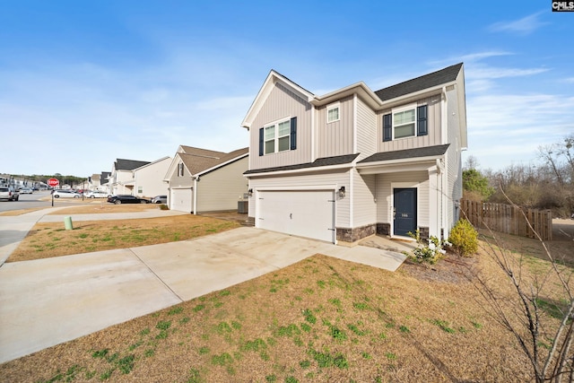 view of front of property featuring a garage, concrete driveway, stone siding, fence, and board and batten siding