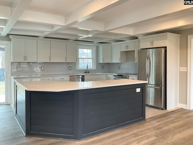 kitchen featuring light wood-style floors, appliances with stainless steel finishes, coffered ceiling, and light countertops