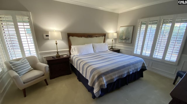 bedroom featuring carpet, a wainscoted wall, crown molding, and multiple windows