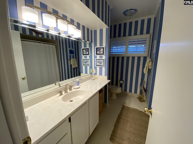 full bath with toilet, wallpapered walls, baseboards, and vanity