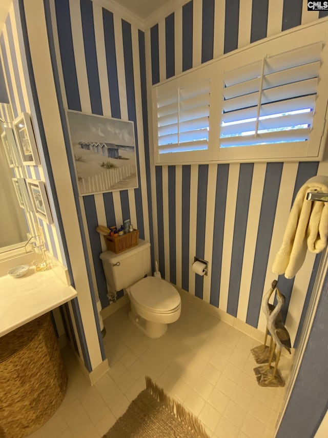 bathroom featuring toilet, wallpapered walls, baseboards, and tile patterned floors