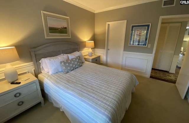 carpeted bedroom with ornamental molding, wainscoting, visible vents, and a decorative wall