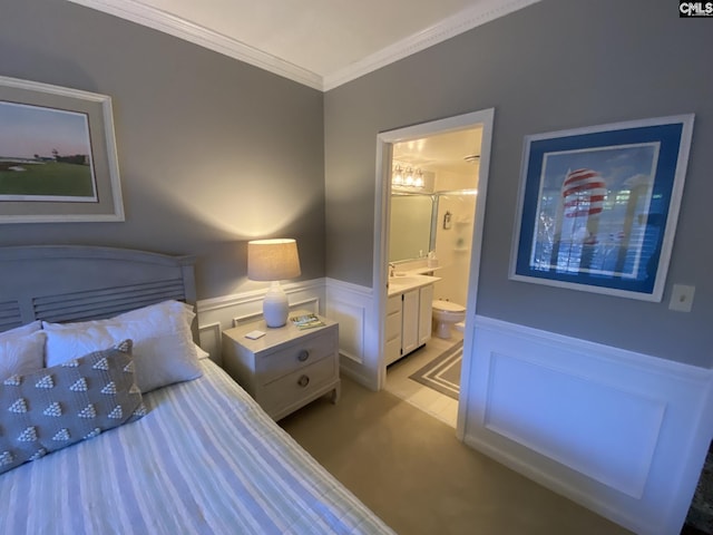 bedroom featuring ensuite bathroom, a wainscoted wall, light carpet, a sink, and crown molding