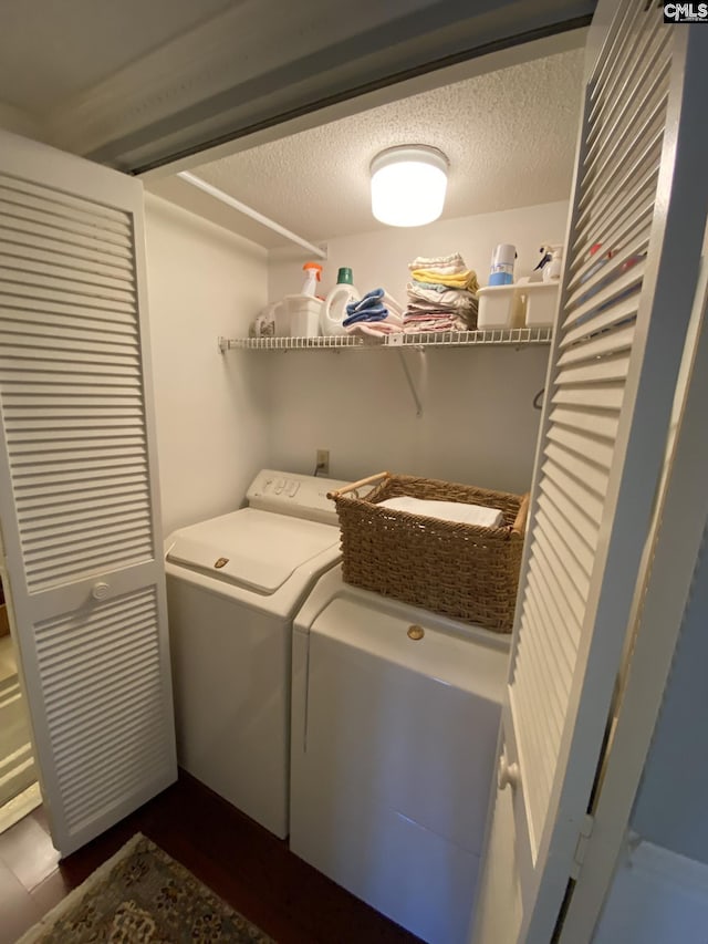 clothes washing area featuring a textured ceiling, laundry area, and washing machine and dryer