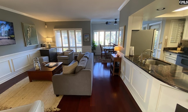 living room with ornamental molding, wainscoting, dark wood-type flooring, and a decorative wall