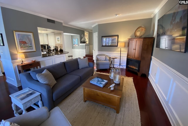 living area with ornamental molding, a wainscoted wall, visible vents, and a fireplace