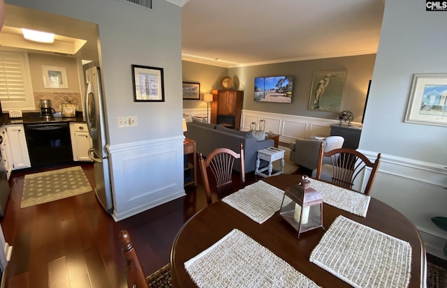 dining room with ornamental molding, dark wood-style flooring, and wainscoting